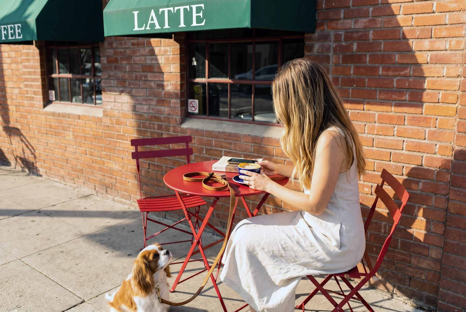 Woman with dog enjoying the neighborhood outside a local coffee shop near Walnut Crossing Pasadena in Pasadena, CA