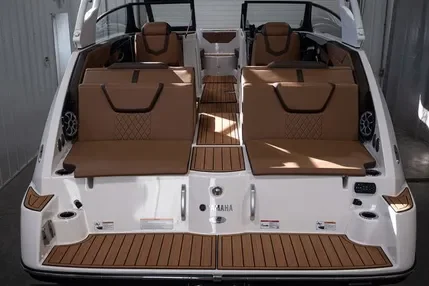 A white Yamaha motorboat with brown seats and wooden deck, viewed from the front in an indoor storage area.