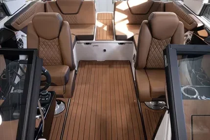 Interior of a boat or yacht with tan leather seats, wood flooring, and control panels.