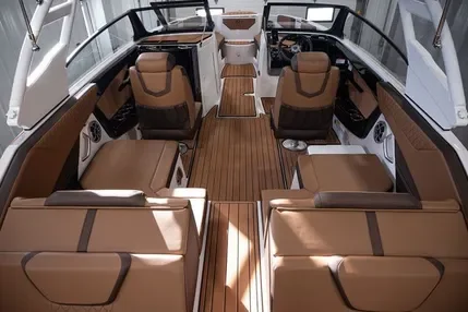 The interior of a luxury boat with brown leather seats, wood flooring, and a steering console with navigation equipment.
