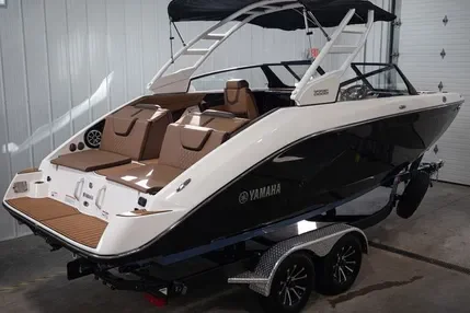 White and black Yamaha motorboat on a trailer inside a garage.