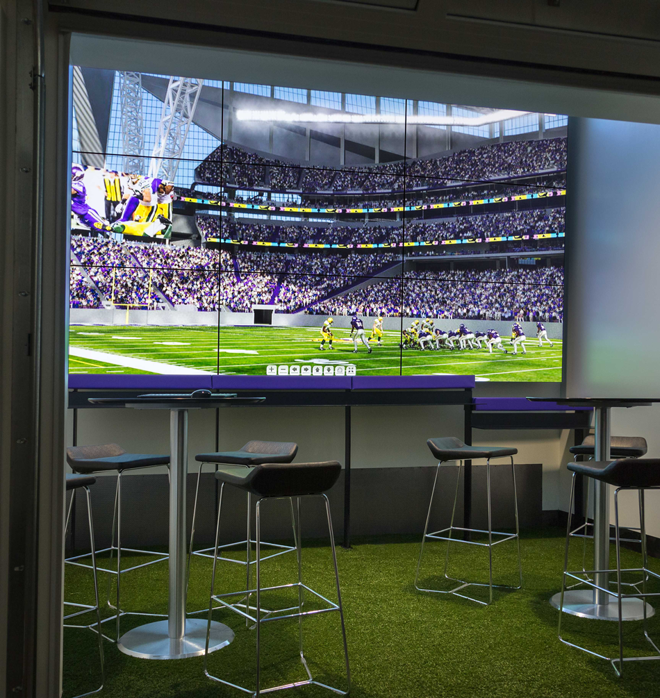 Large multi-screen video wall displaying Minnesota Vikings football inside the U.S. Bank Stadium Preview Center.