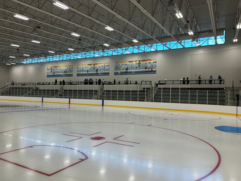 Wide interior view of Hasse Ryt-Way Arena showing the hockey rink, spectator seating, and overhead arena lighting.