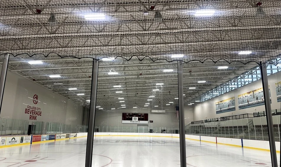 Interior view of the ice rink at Hasse Ryt-Way Arena in Northfield, Minnesota, showing the ice surface, protective netting, and overhead lighting.