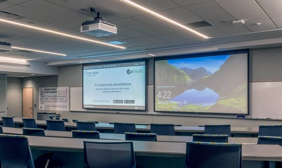 Concordia College Integrated Science Center classroom in Moorhead, Minnesota, featuring dual projection screens, ceiling-mounted projectors, and integrated audiovisual presentation technology.