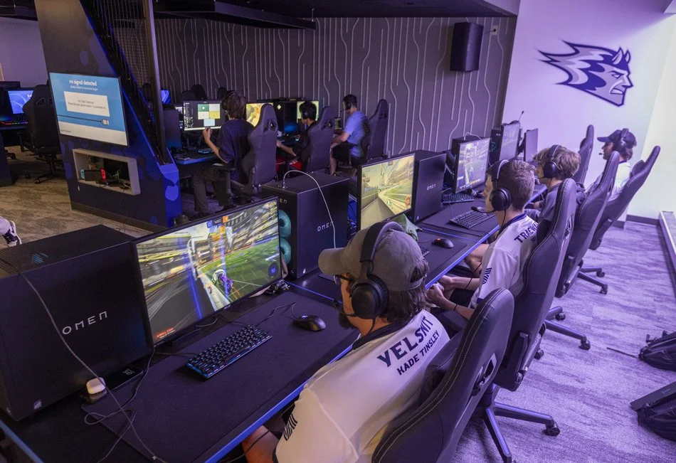 UW-Stout esports players competing at gaming stations equipped with high-performance monitors and headsets inside the Polytechnic Esports Arena.