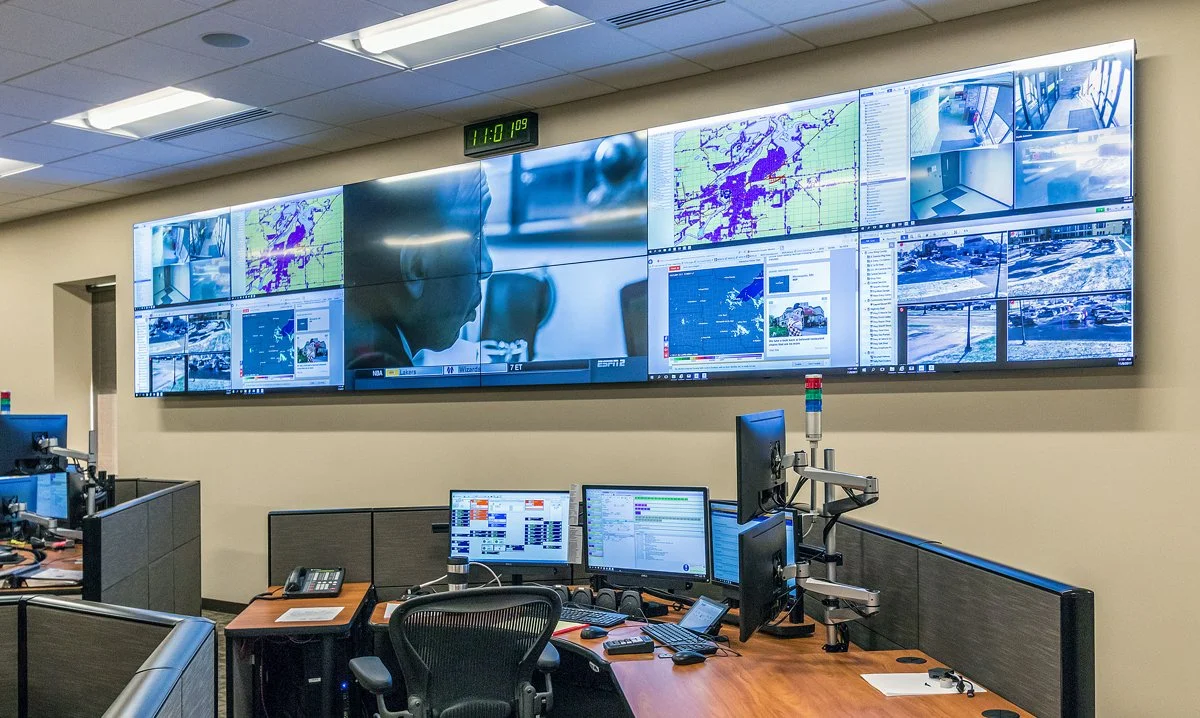 Crow Wing County Public Safety Dispatch Center featuring a 24-foot-wide, 12-screen video wall displaying security cameras, maps, and monitoring feeds above emergency dispatch workstations.