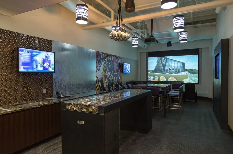 Minnesota Vikings U.S. Bank Stadium Preview Center lounge featuring wall-mounted digital displays, a large projection screen, and integrated audiovisual technology.