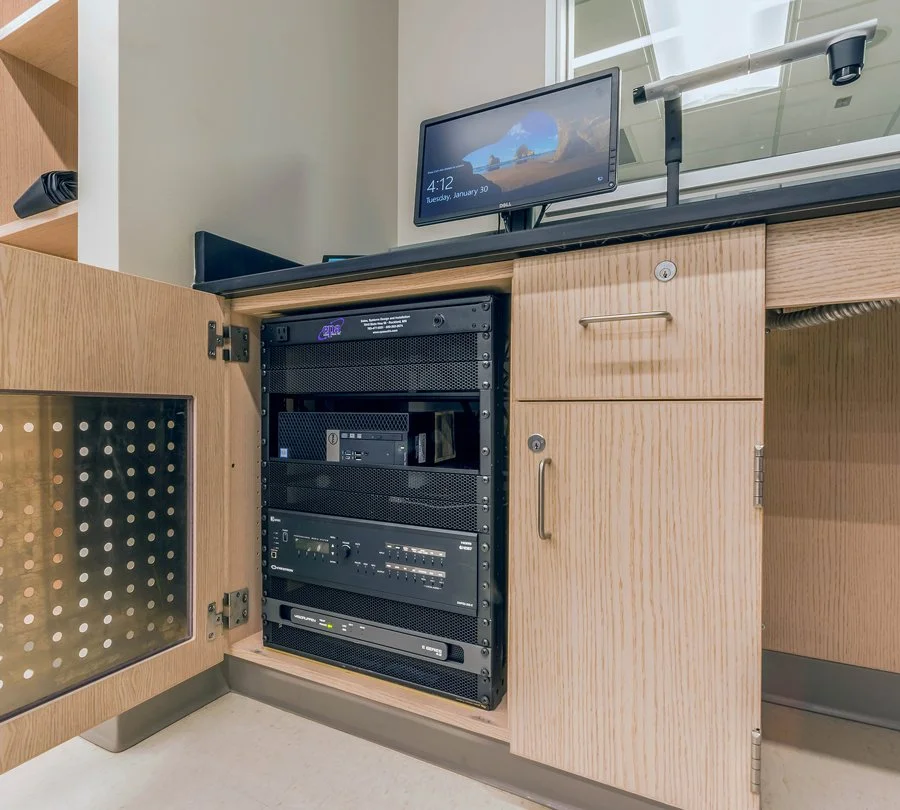 Integrated audiovisual equipment rack housed inside a classroom cabinet at Concordia College, supporting classroom presentation and control systems.