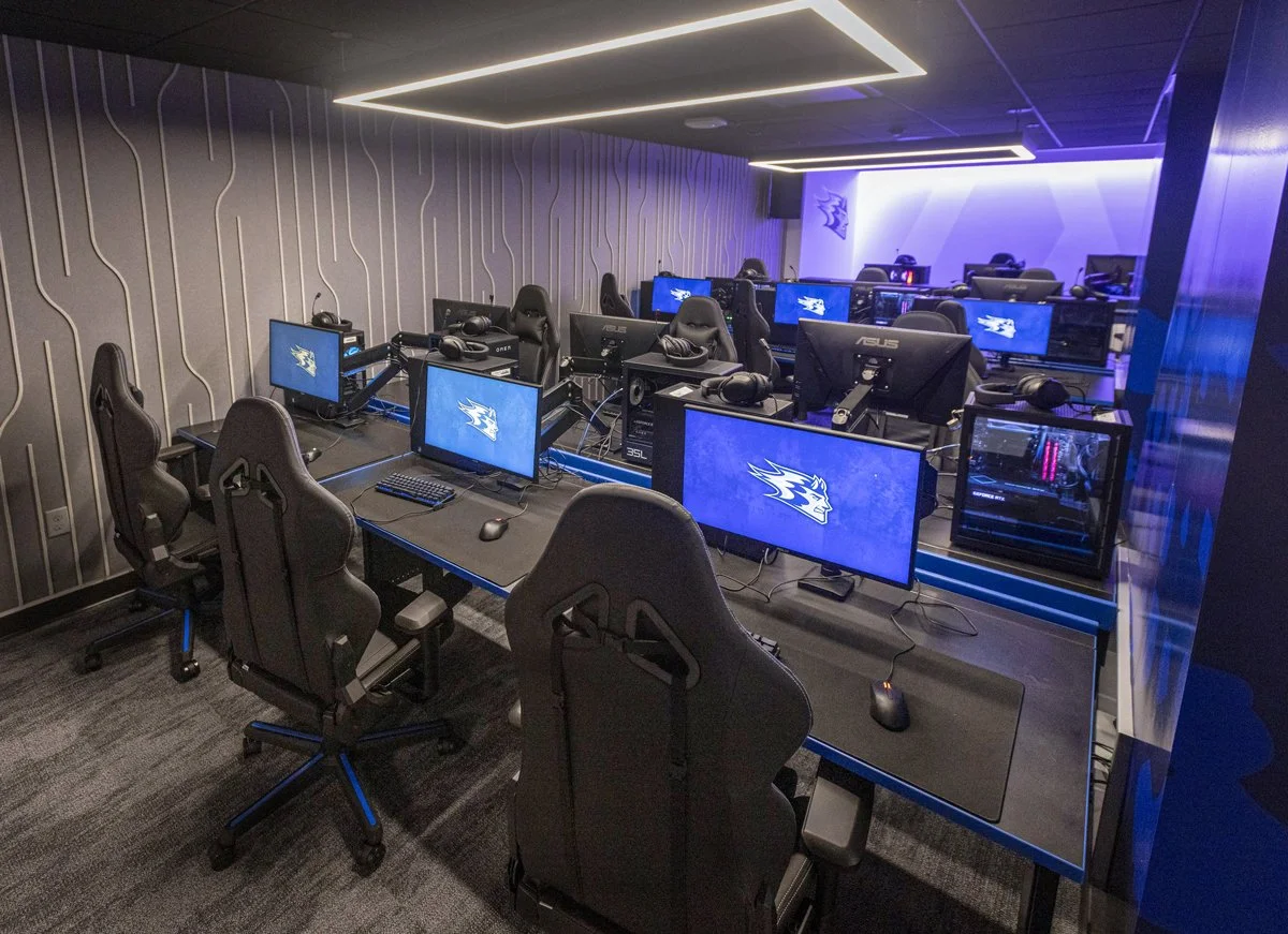 UW-Stout Polytechnic Esports Arena featuring rows of gaming computers, monitors, headsets, and gaming chairs with Blue Devils branding.