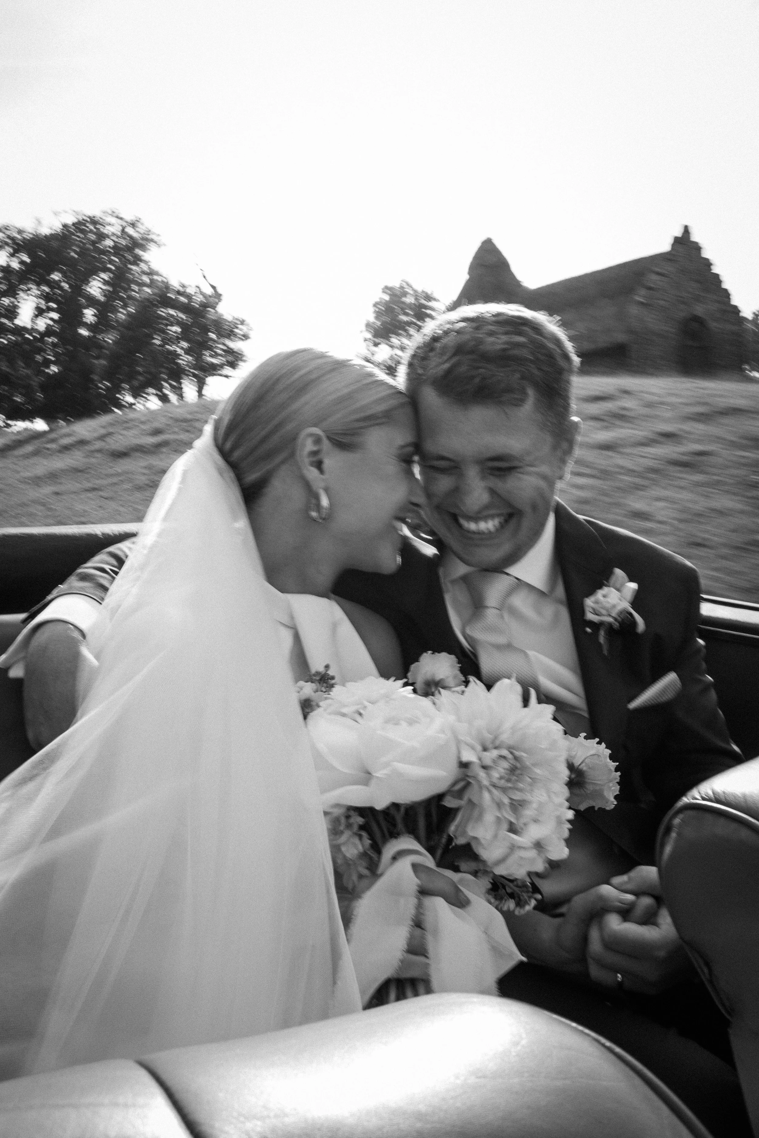Joyful newlywed couple in vintage wedding car