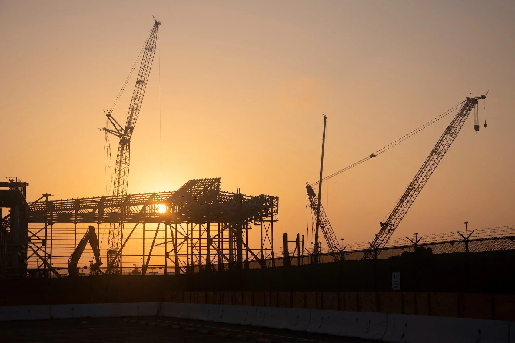 steel frame of an airplane hangar being constructed at sunrise