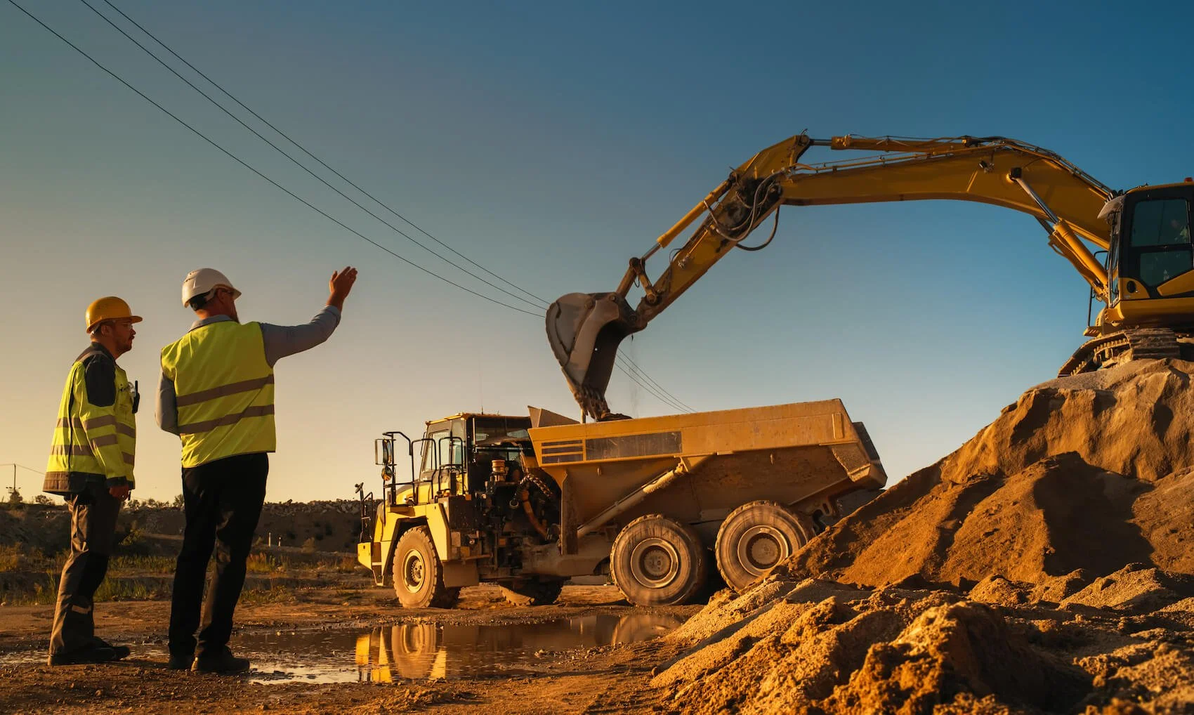 Engineers talking at a dirt Construction Site with dump truck and excavator in background