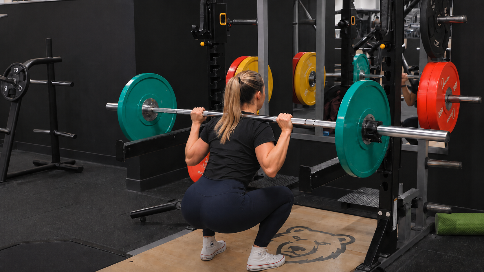 Female volleyball athlete performing a barbell back squat in a rack to build lower body strength for ACL prevention.
