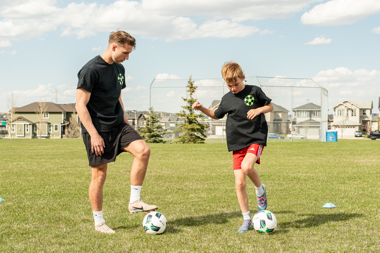 Youth soccer player improving ball control and footwork with a coach during a soccer skills training session in Calgary.
