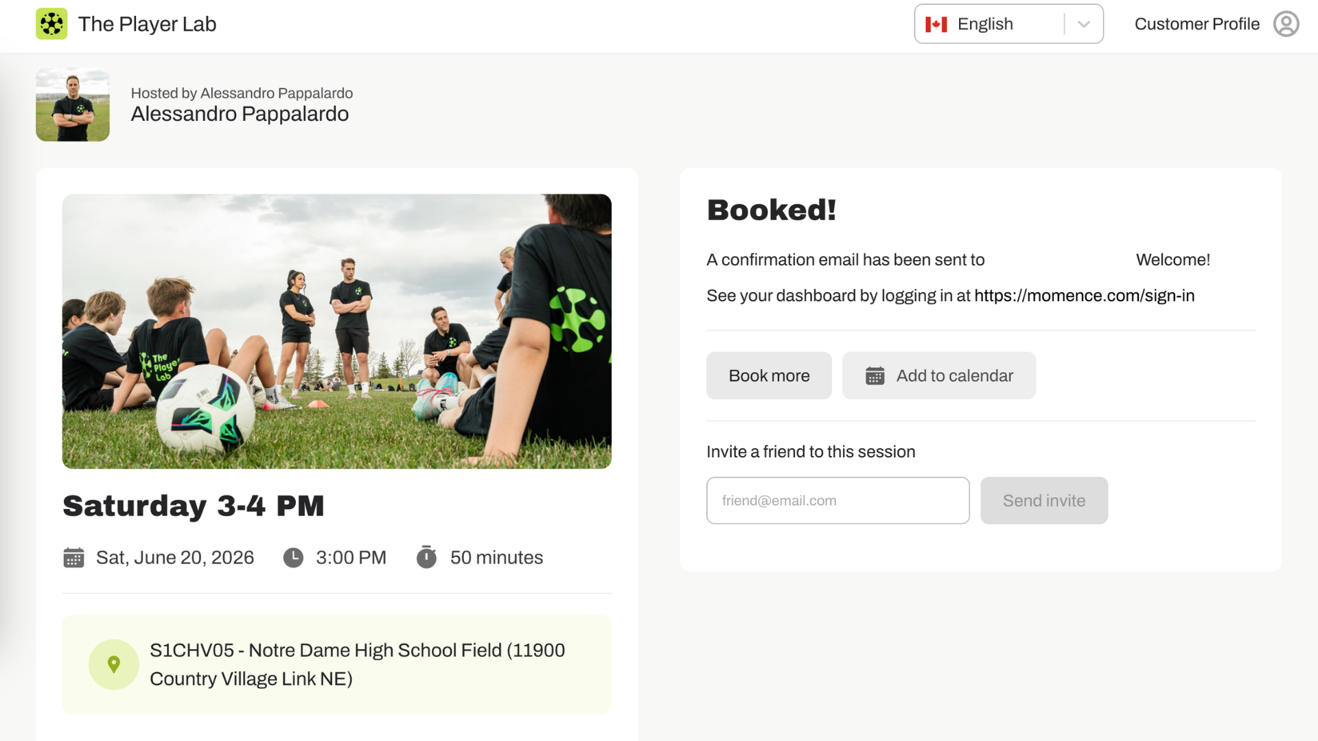 A group of young people in black sportswear with green logo, sitting on grass with soccer ball, listening to coach during outdoor soccer practice or game on a cloudy day.