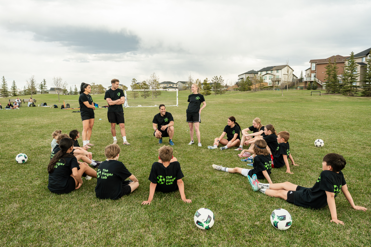 Youth soccer players receiving coaching instruction during a soccer training session in Calgary focused on player development and confidence on the ball.