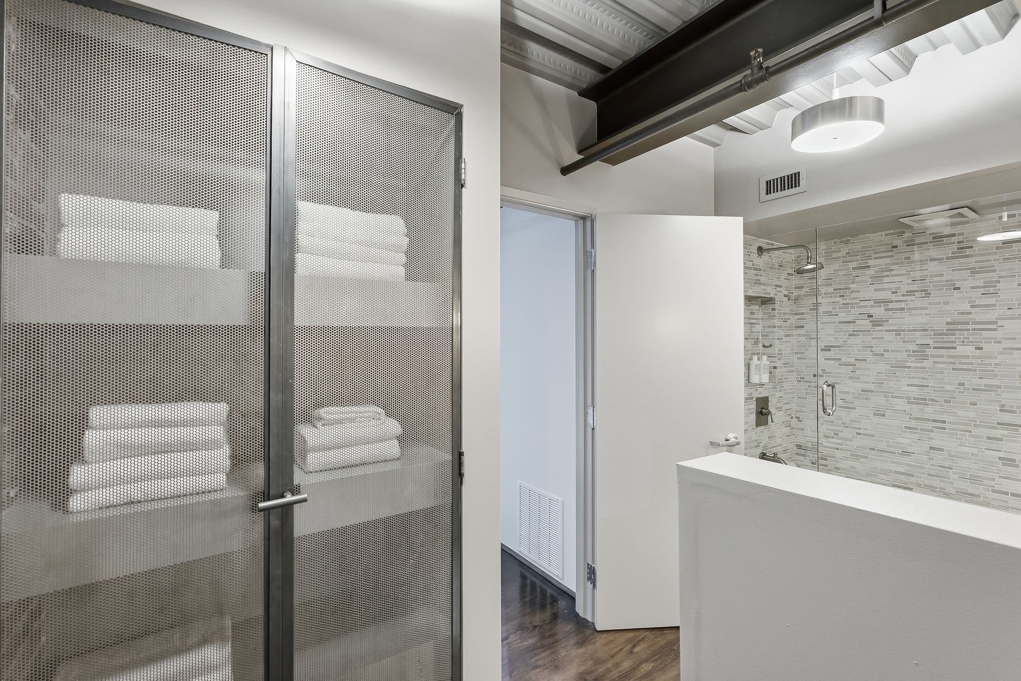 Bathroom with a walk-in shower and a cabinet with shelves containing towels.