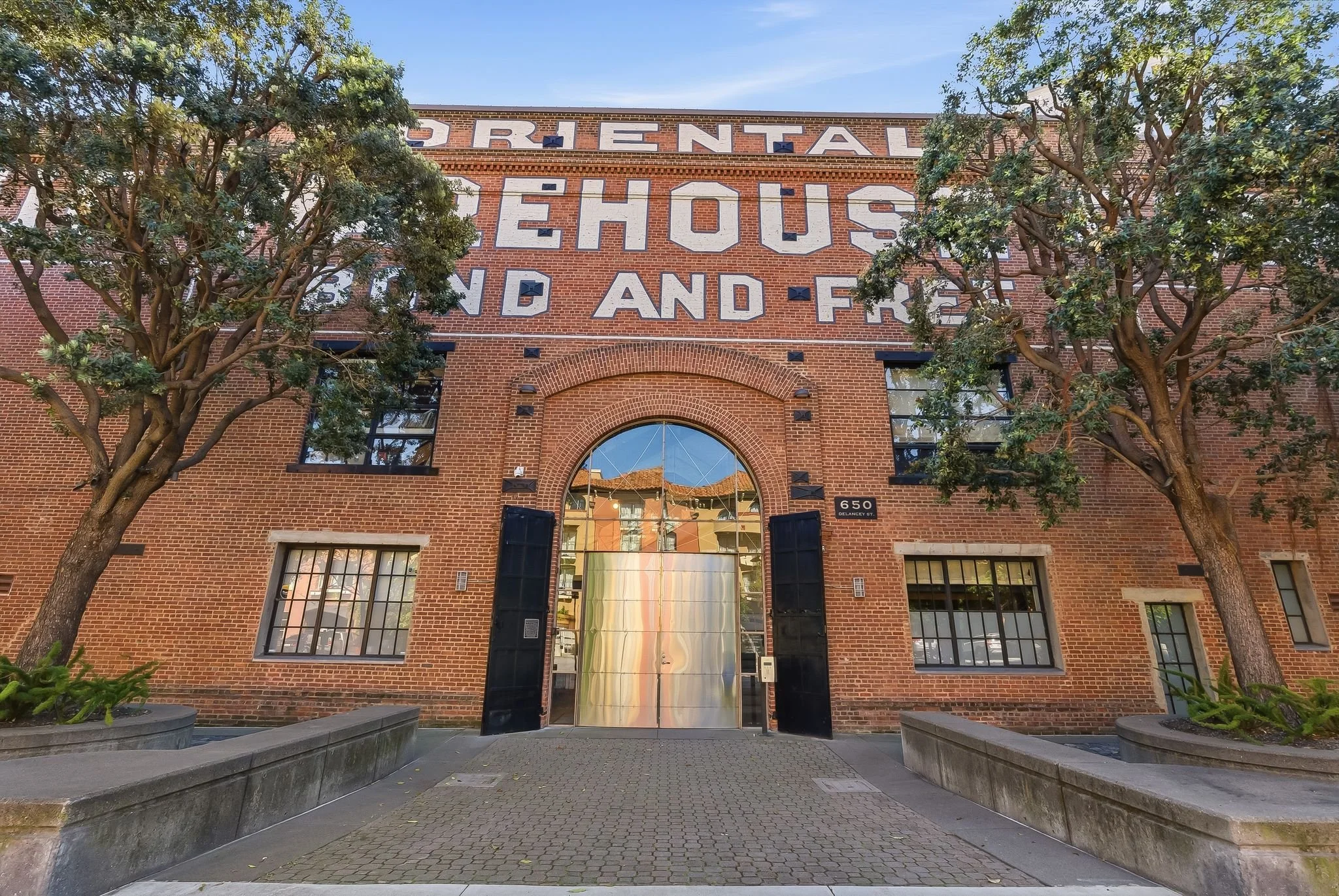 Front view of a red brick building with large sign reading 'Cretal Ehouse and F' on top. The building has multiple black-framed windows and a glass entrance door with a brick arch. Two trees are on either side of the entrance.
