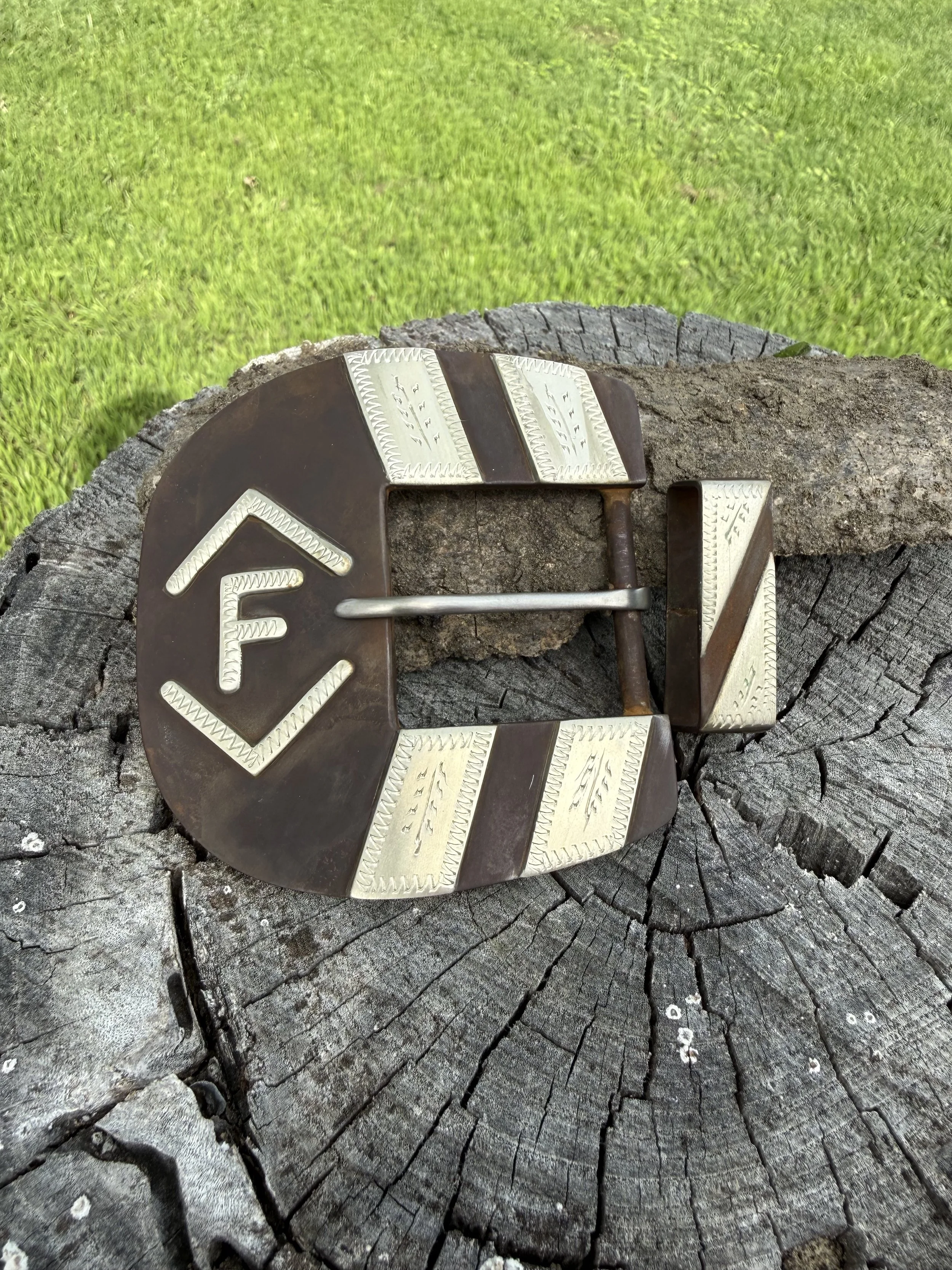 A vintage metal latch on a weathered tree stump with bright green grass in the background.