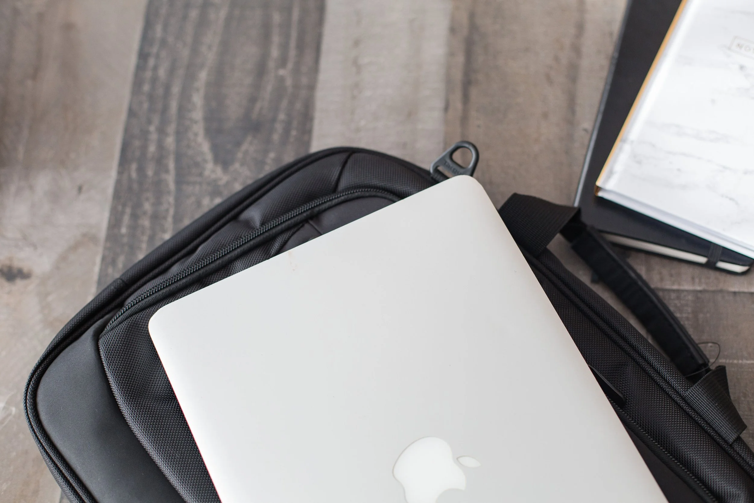 laptop on top of laptop bagel with notebooks beside it