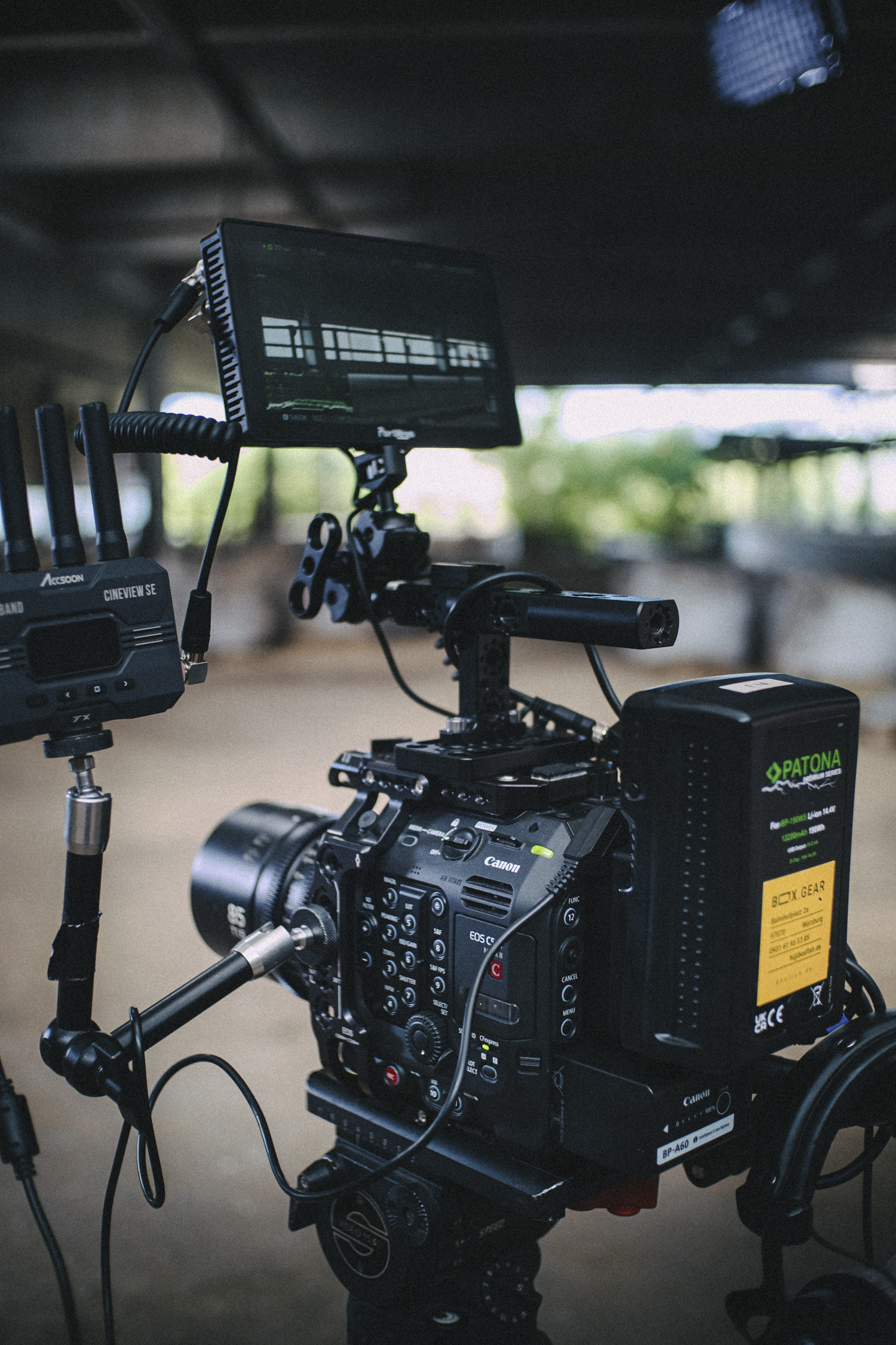 Close-up of a professional video camera setup with a monitor and accessories in an indoor or outdoor setting.