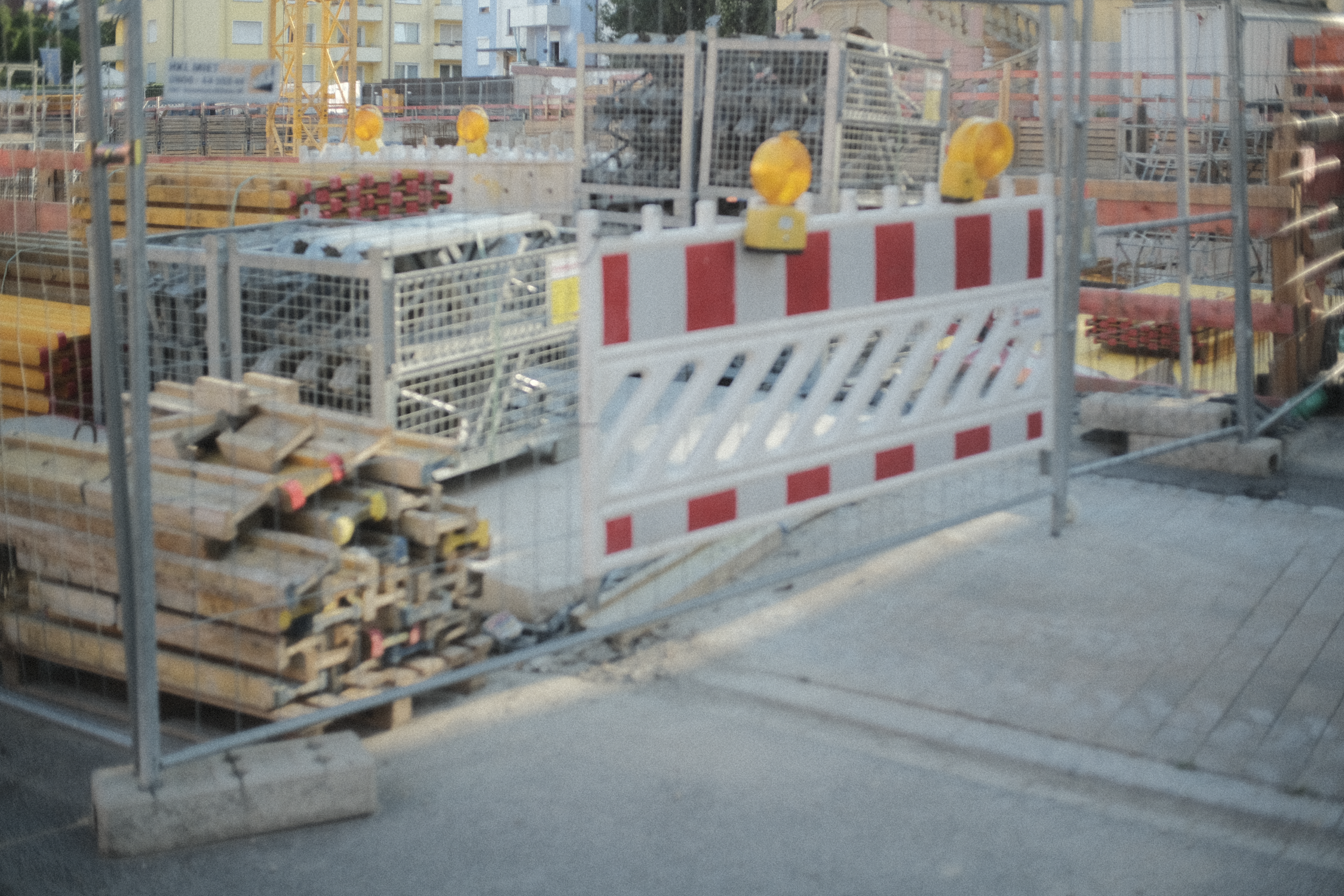 Construction site with barricades, yellow warning lights, and various building materials such as wood and metal scattered around.