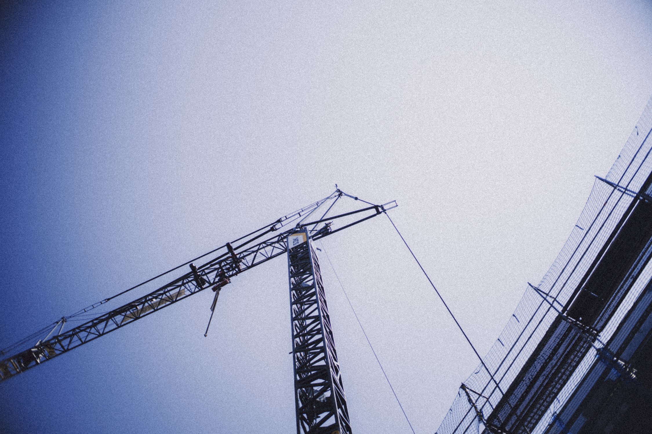A construction crane on a building site against a partly cloudy sky.