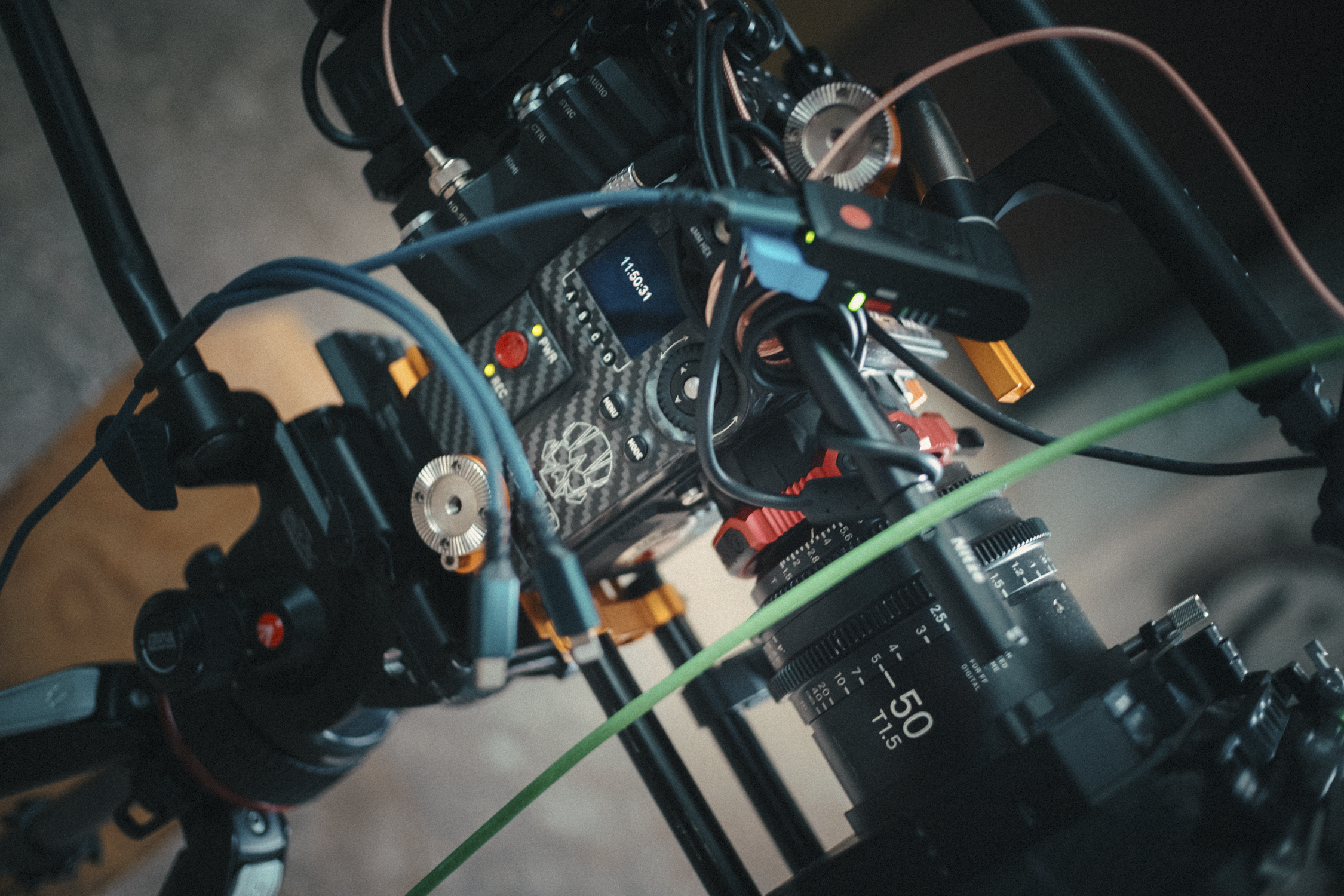 Close-up view of a professional camera mounted on a rig with various cables and dials, used in filmmaking or video production.