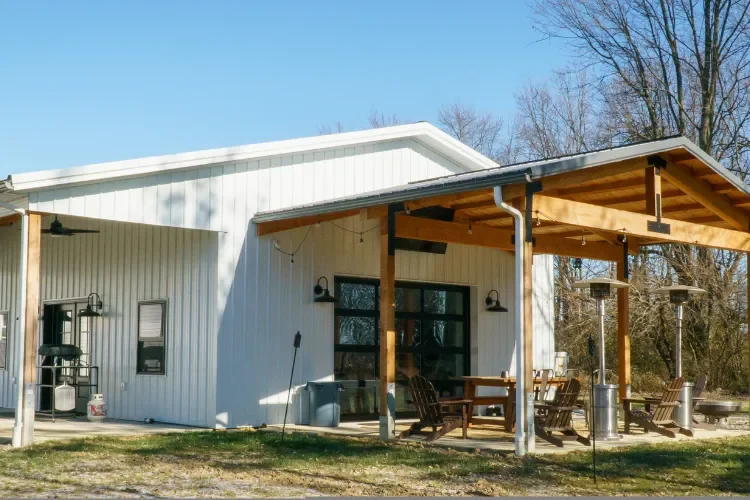 White house with a covered porch area, outdoor dining table, and patio heaters