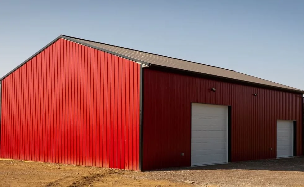 Red metal storage building with two white garage doors and a sloped roof, against a clear sky.