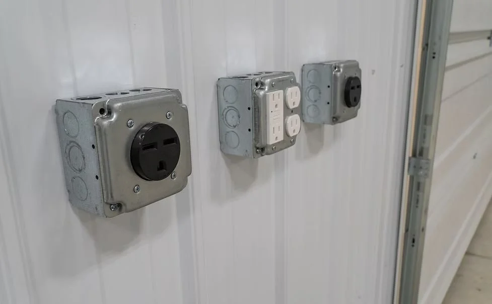 Three electrical outlets and switches mounted on a white wall.