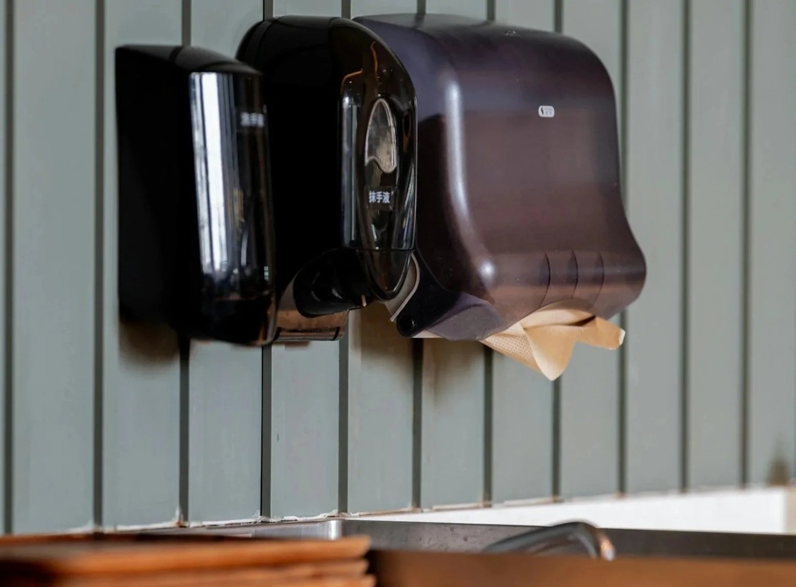 A wall-mounted black paper dispenser