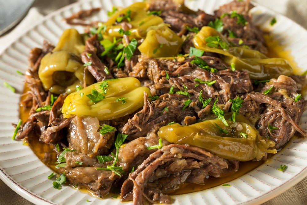Shredded beef with green chili peppers garnished with chopped parsley on a white plate.