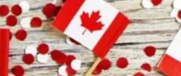 Red and white confetti and a small Canadian flag are scattered on a wood surface
