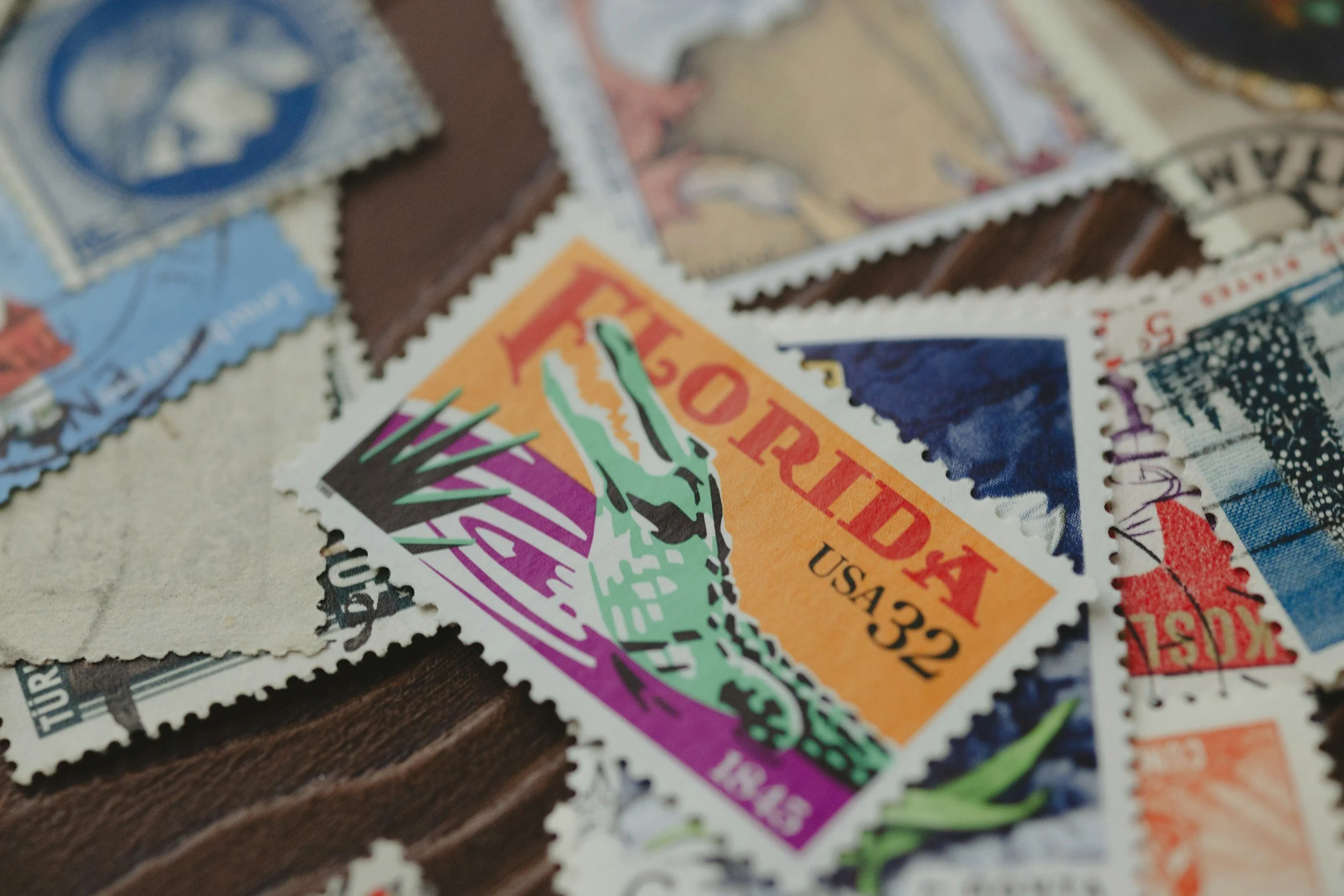 Close-up of vintage postage stamps featuring colorful designs and varied motifs, arranged overlapping on a surface.