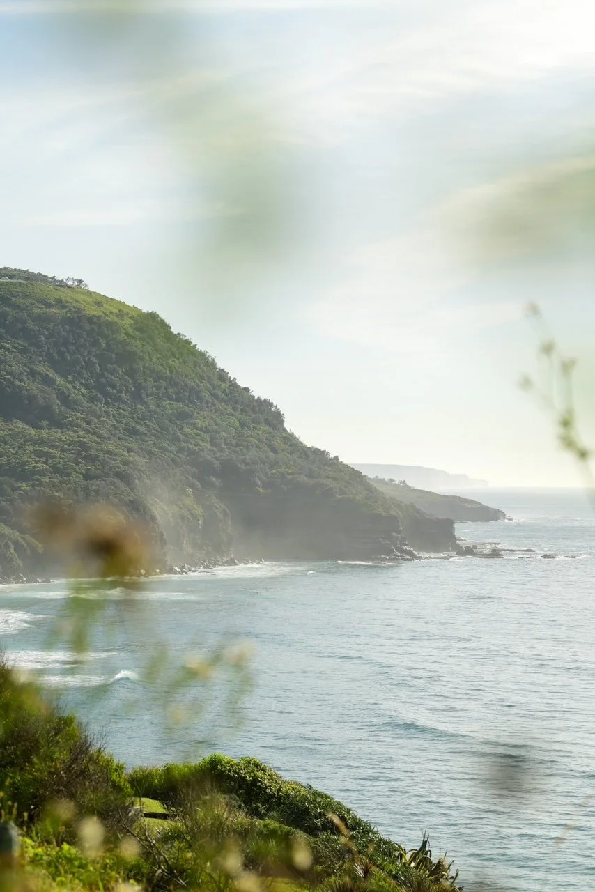 Coastal view of green cliffs, ocean waves, and cloudy sky