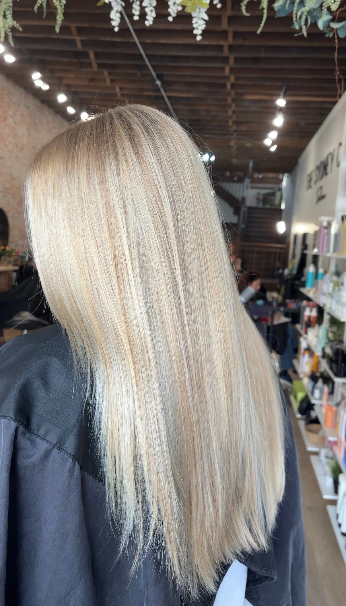 Long, straight, blonde hair with subtle highlights, worn by a person in a salon or beauty shop.