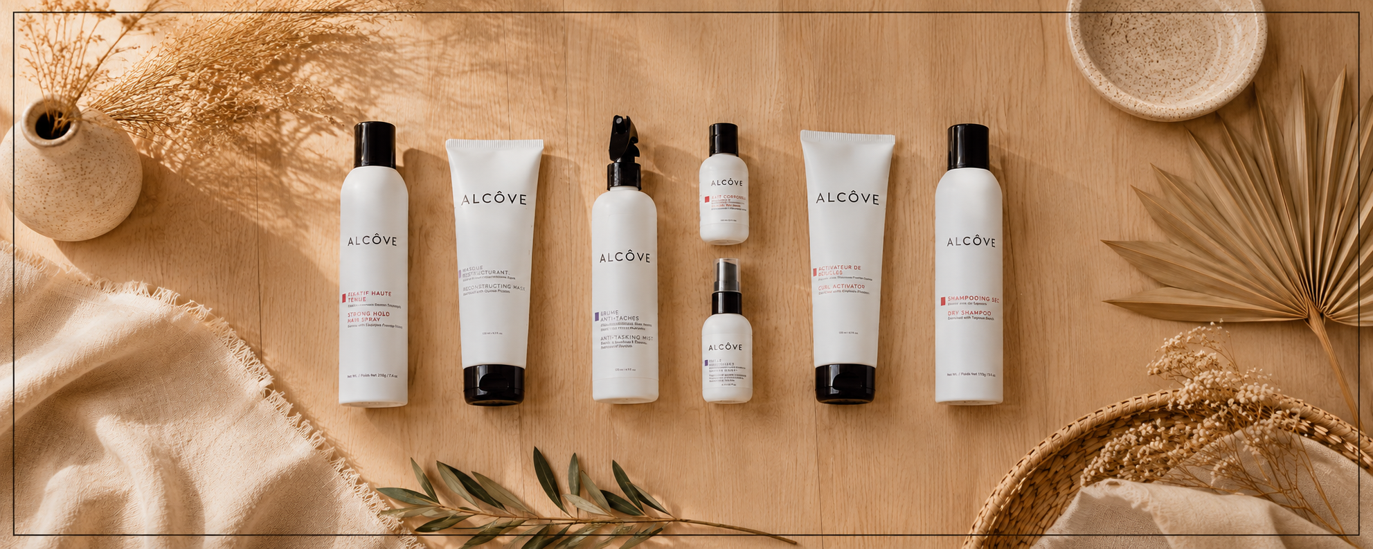 A flat lay of skincare and haircare products on a wooden surface, accompanied by dried leaves, a wicker basket, and ceramic bowls.