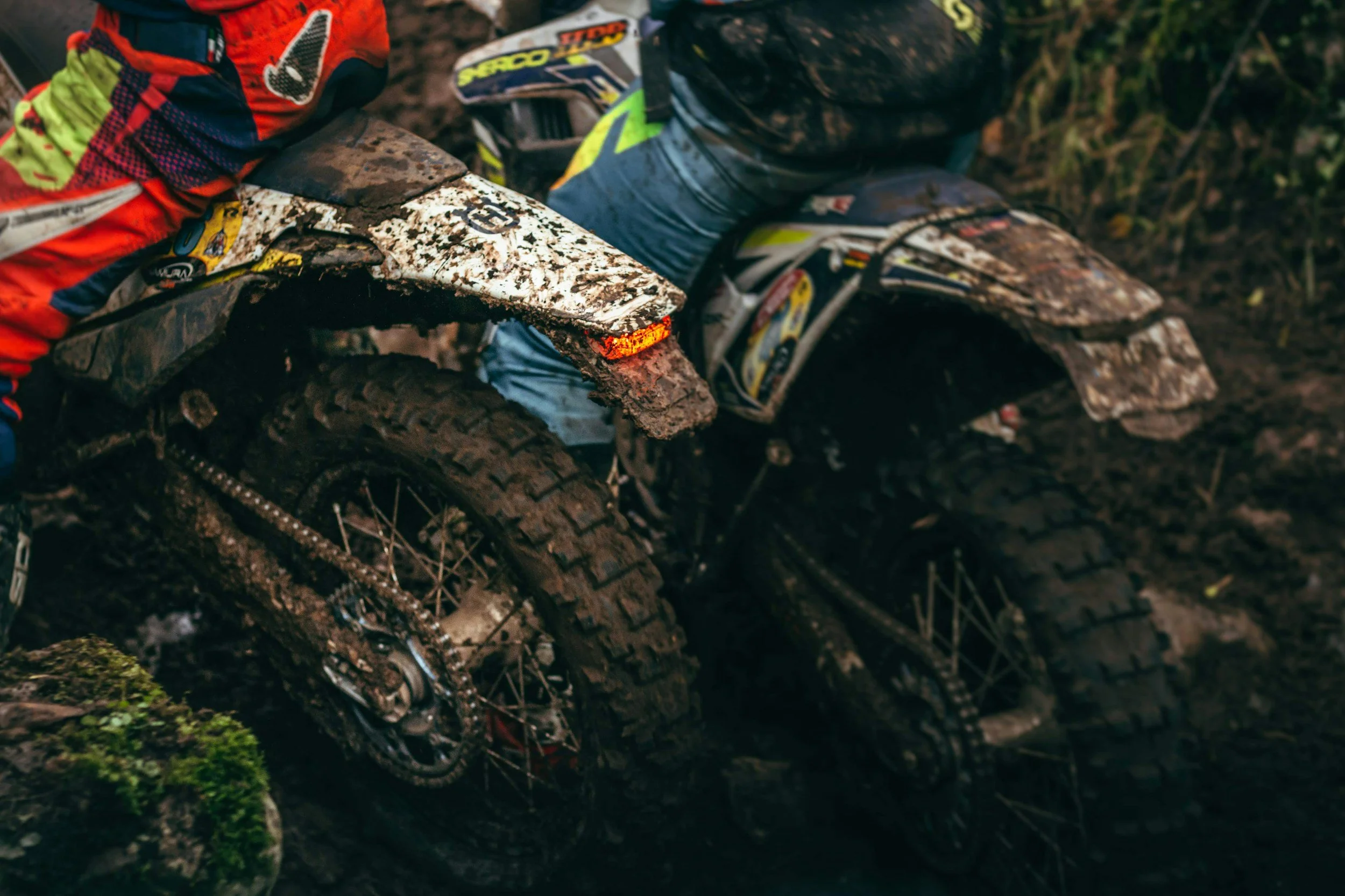 Mud-covered dirt bike motorcycle off-road in a muddy forest trail.