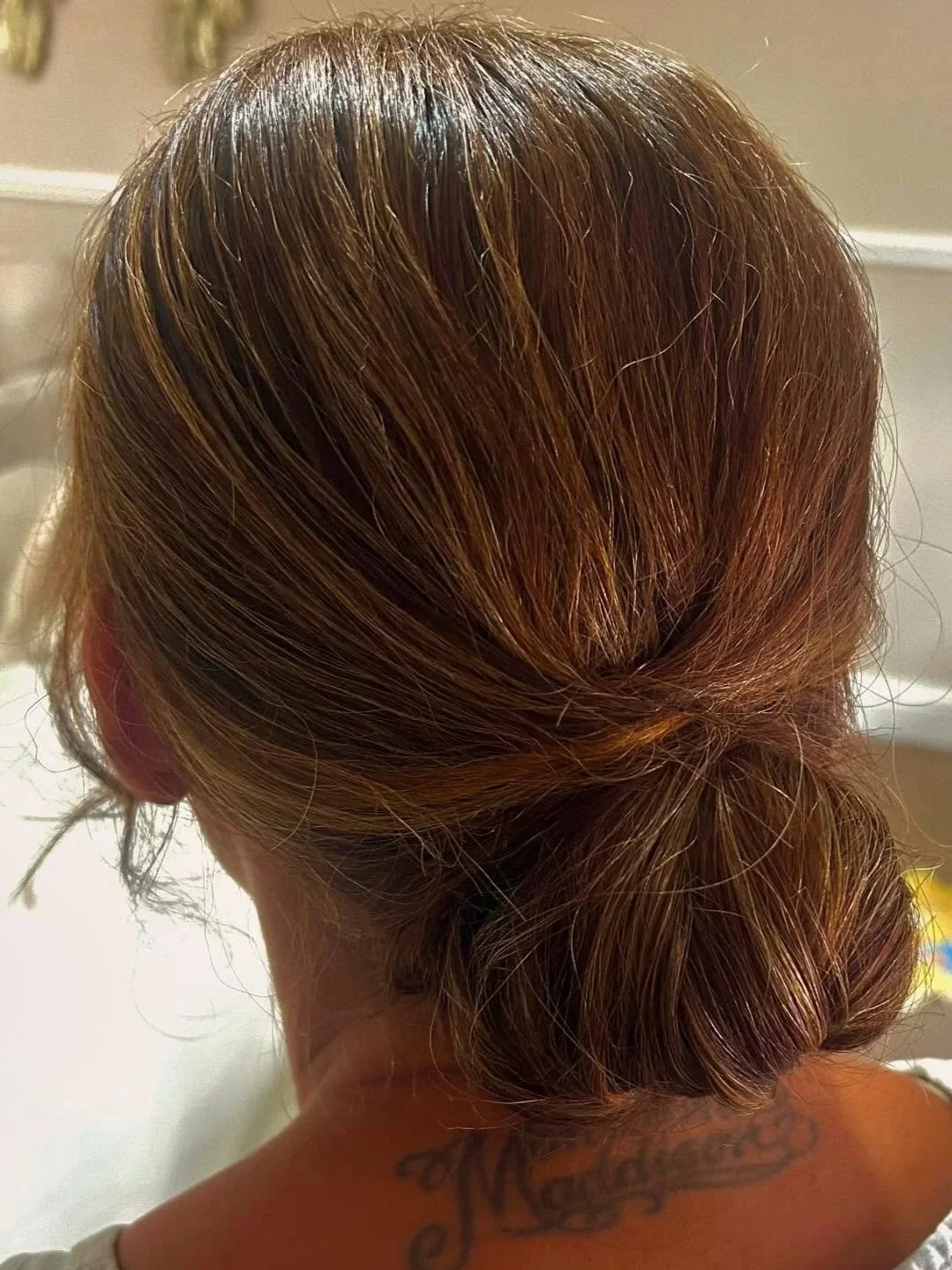 Back of a person's head with medium-length brown hair styled in a loose bun.