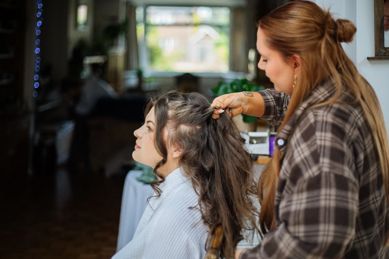 A woman with long, curly hair having her hair styled by a hairstylist in a salon.