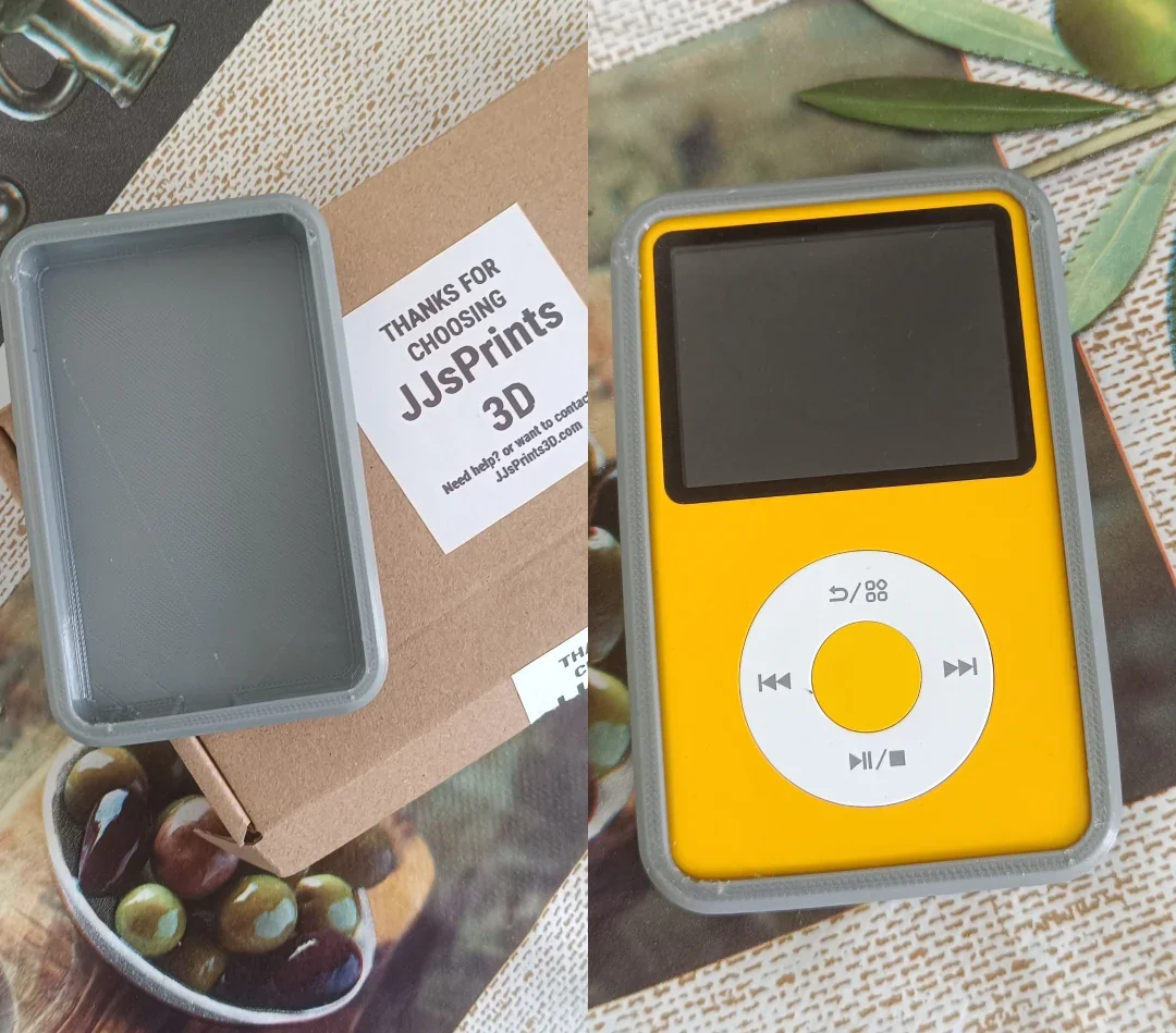 An iPod Classic with a yellow case, a black screen, and white circular control wheel. The iPod is placed on a surface with some green leaves nearby. Next to it is a cardboard box with a thank you note that reads "Thanks for choosing JJ Sprints 3D".