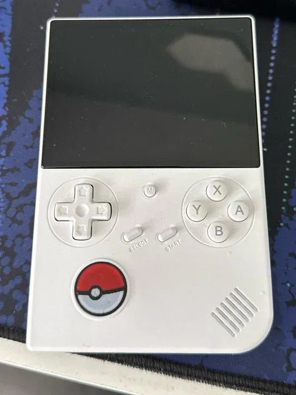 A white handheld gaming device with a black screen, a directional pad, A, B, X, Y buttons, and a Pokéball button, resembling a Pokémon-themed Nintendo Game Boy.
