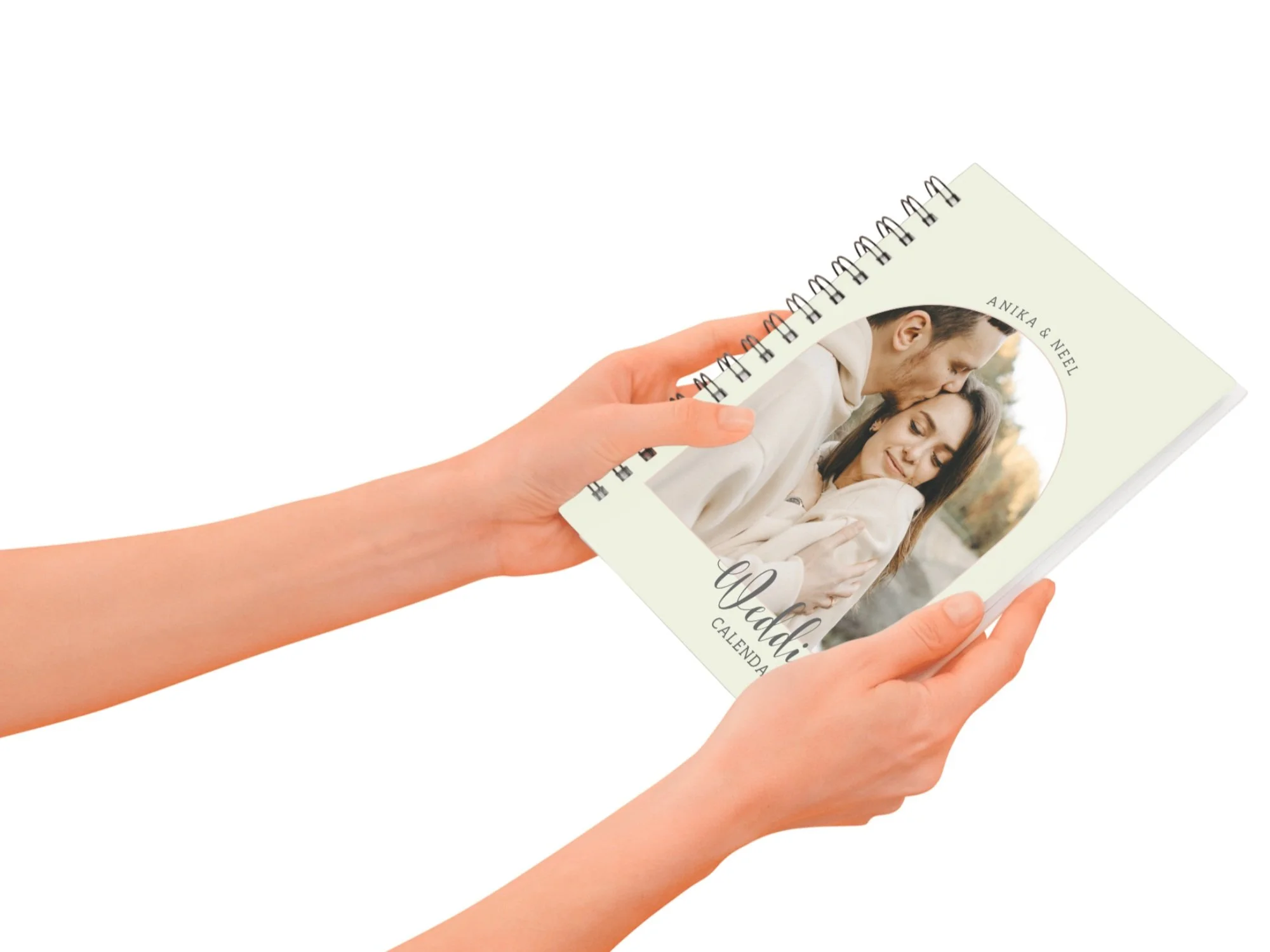 Person holding a spiral-bound calendar featuring a photo of a couple embracing outdoors, titled 'Countdown Calendar'.