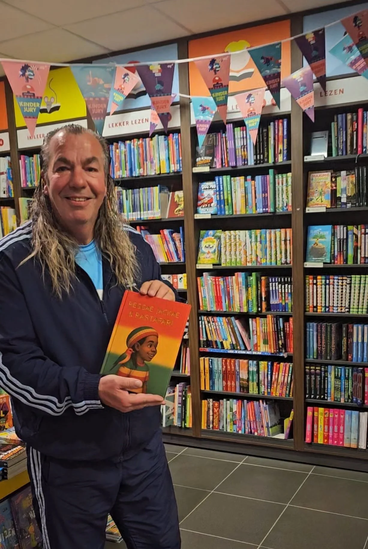 Auteur Jacky Krassenburg met het kinderboek Reggae Jackae en Rastafari in handen