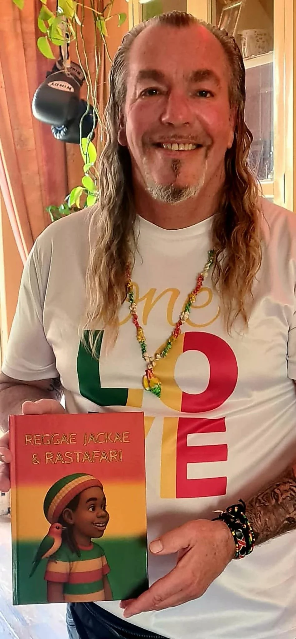Auteur Jacky Krassenburg toont het kinderboek Reggae Jackae en Rastafari