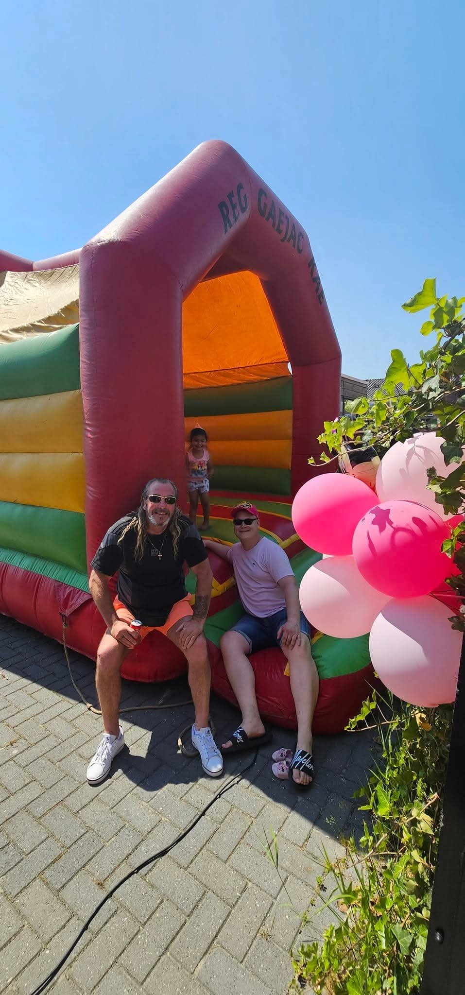 Springkussen verhuur voor kinderfeestje met ouders en spelende kinderen in kleurrijke reggae stijl