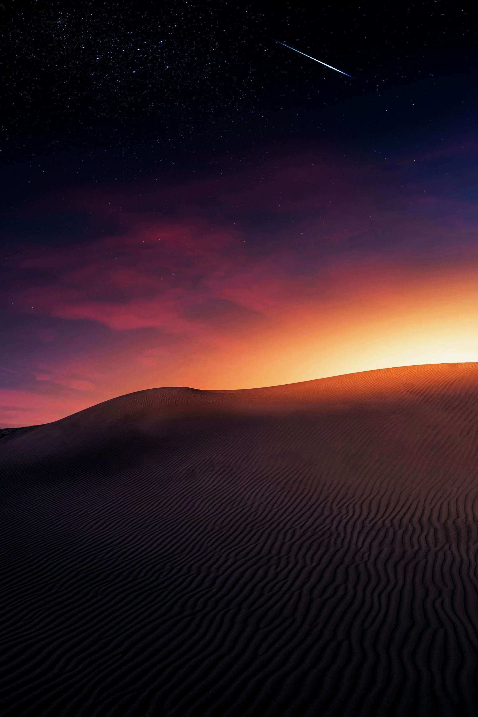 Atmospheric night sky with a shooting star over dark dunes.