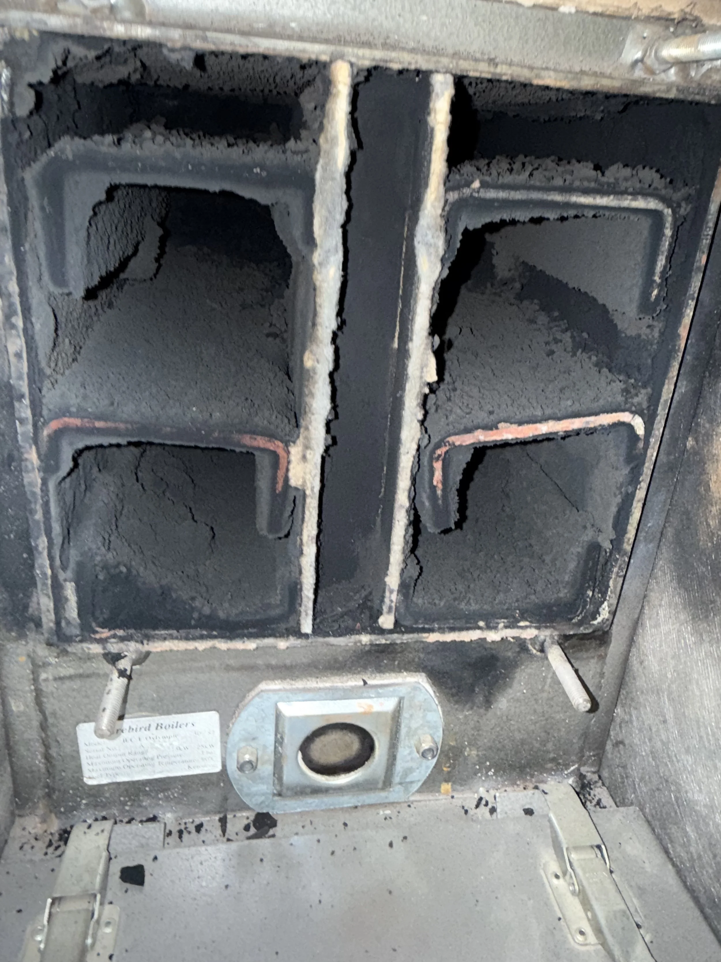 Burned-out stove with blackened interior, missing burners, and soot around the area.